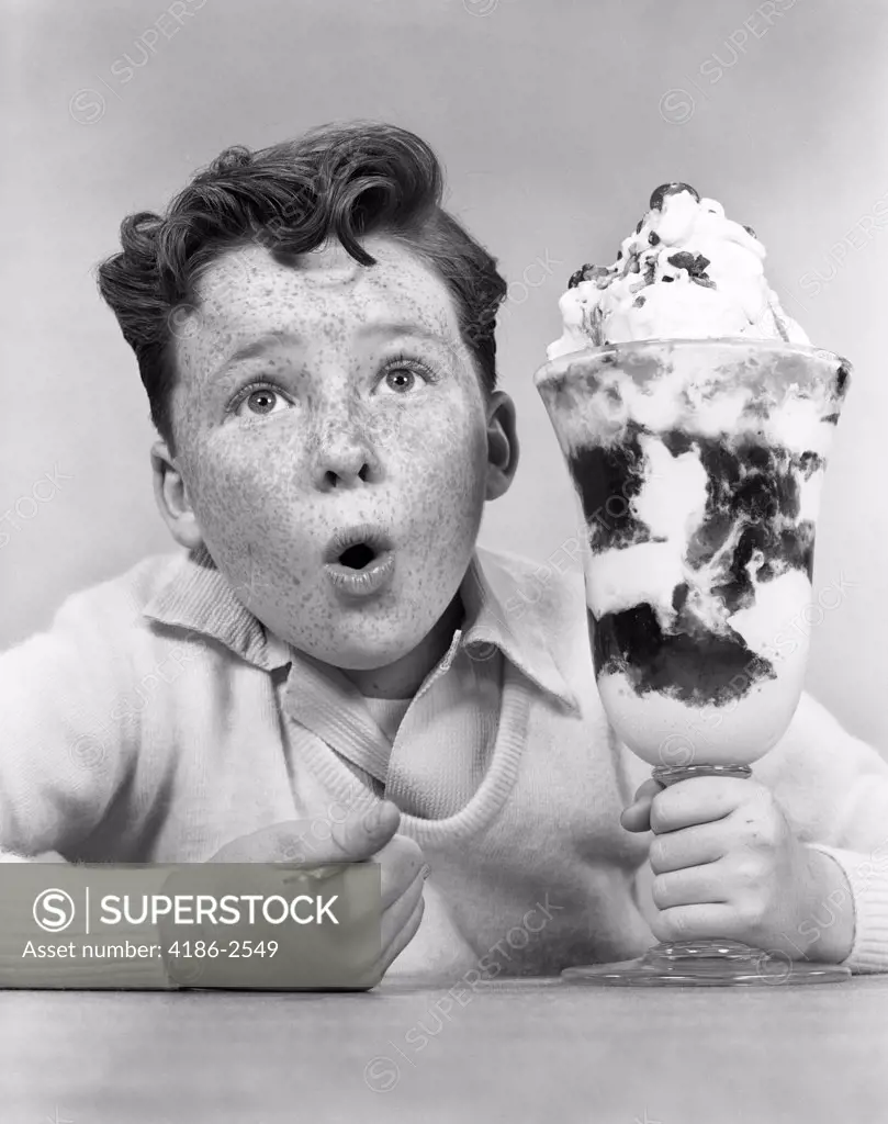 1950S Freckle Faced Boy With Funny Expression Looking At Giant Sized Ice Cream Sundae Parfait