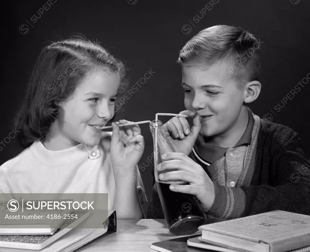 1980S Boy And Girl Sharing Single Bottle Of Soda With Two Straws At Table With Books Inside