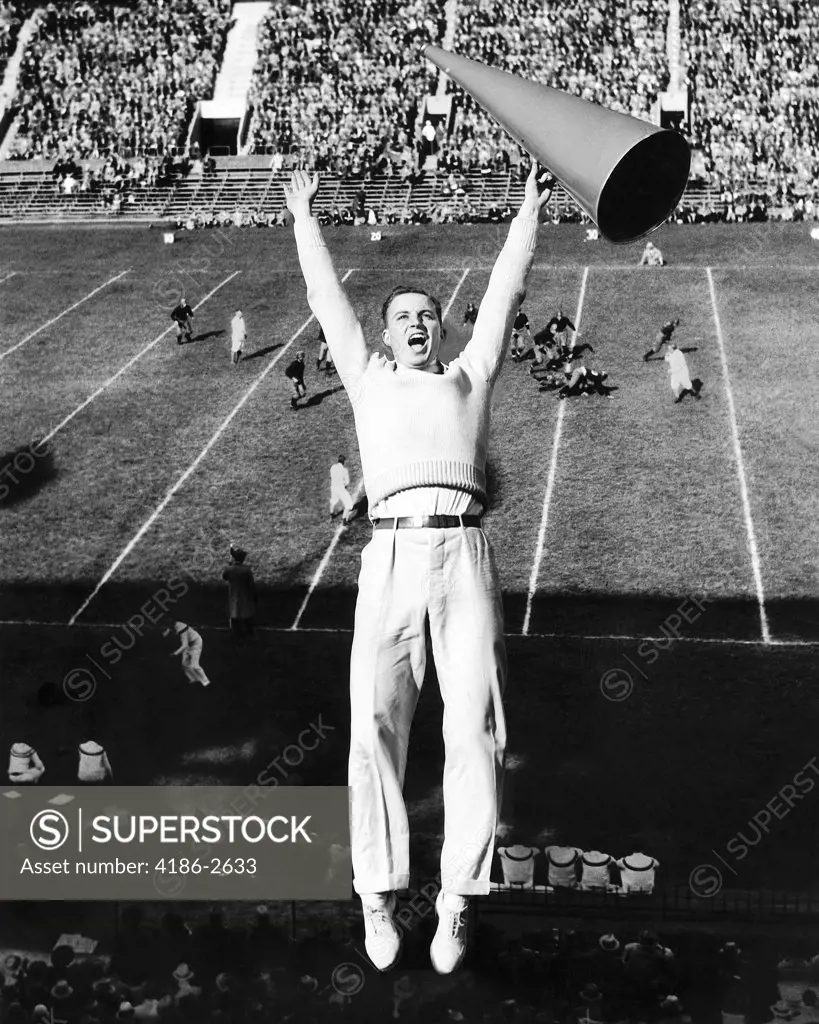 1940S Male Cheerleader With Megaphone Jumping In Air At Football Game