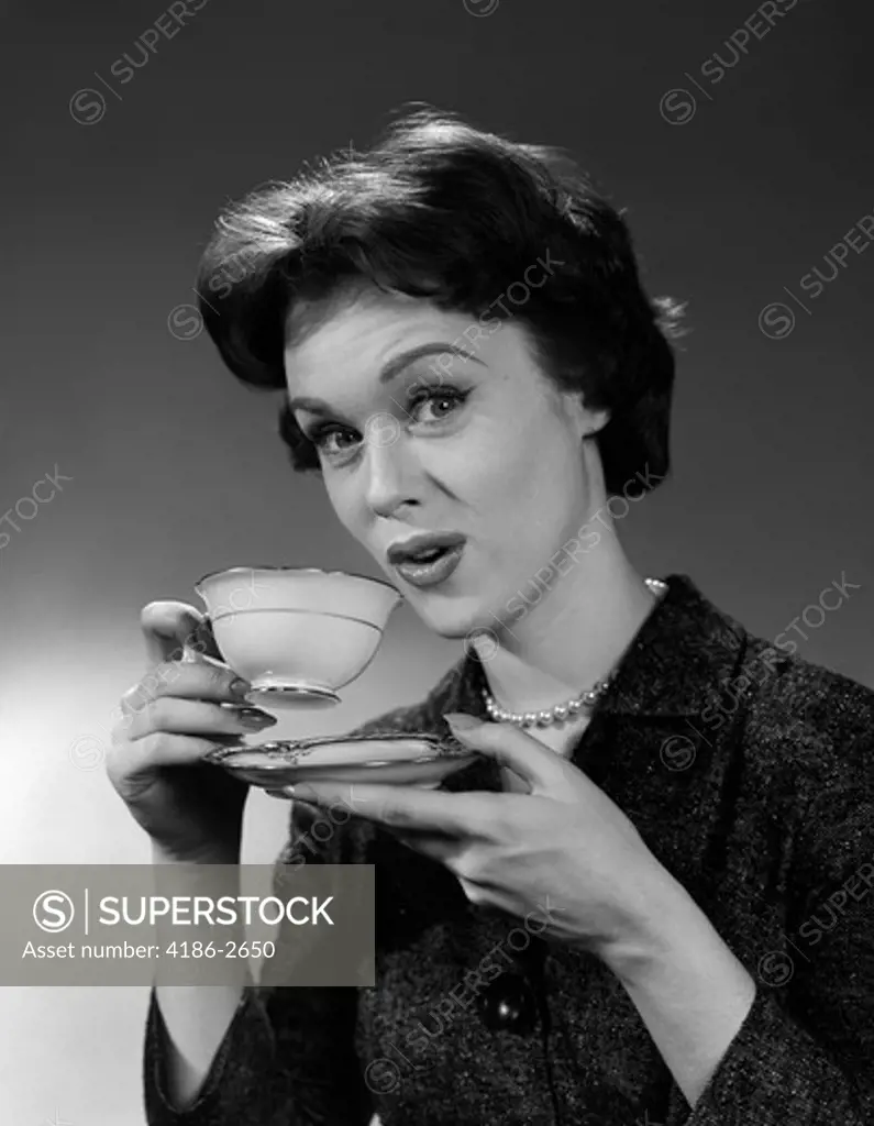 1950S Woman Holding Cup And Saucer Drinking Tea Or Coffee Looking At Camera