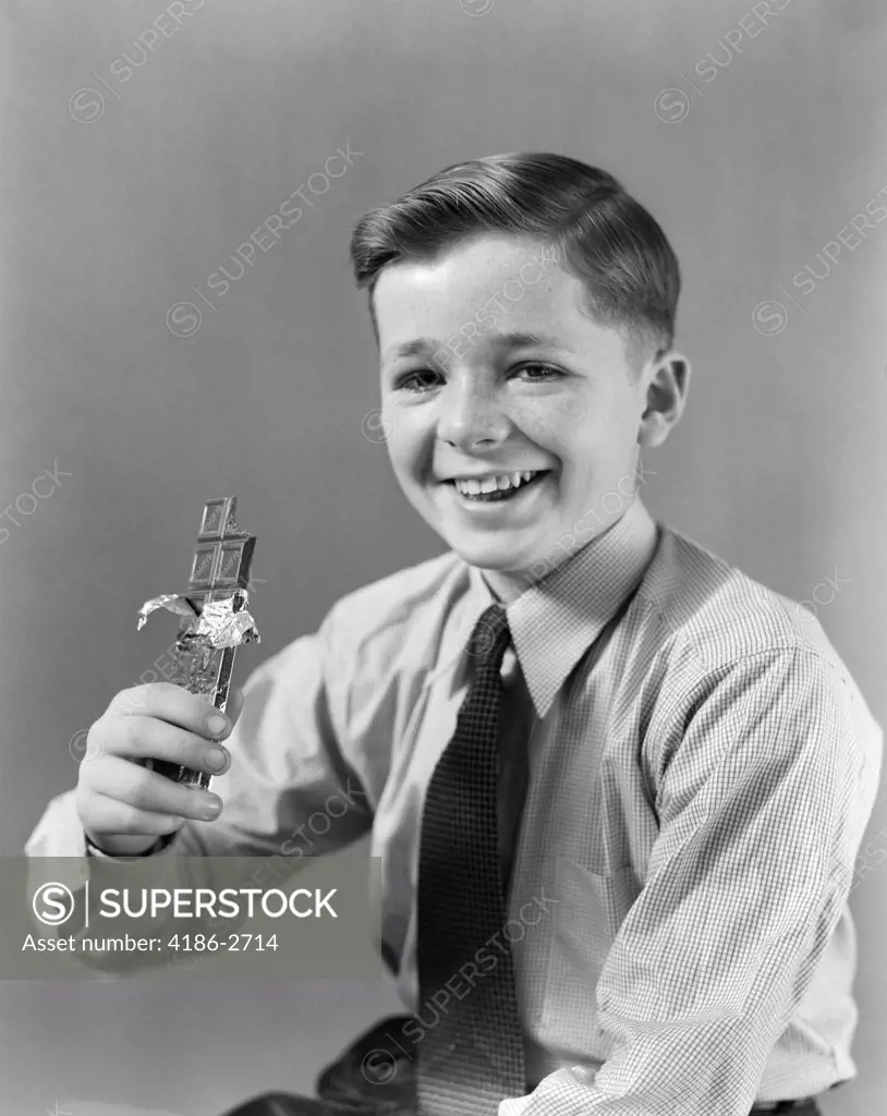 1940S Smiling Boy Holding Eating Candy Bar Chocolate Looking At Camera