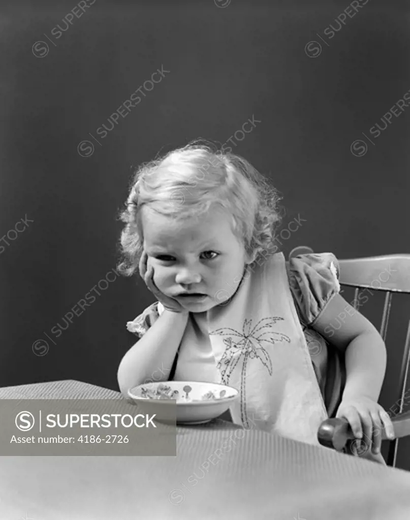 1930S 1940S Sad Baby Girl At Table With Cereal Bowl