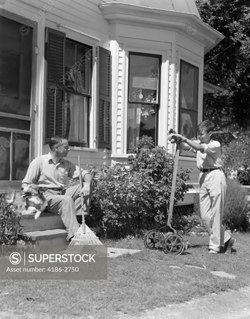 1940S Father Sits On Porch Steps Holding Rake Talking To Son Standing Holding Lawnmower Backyard Window Doorway