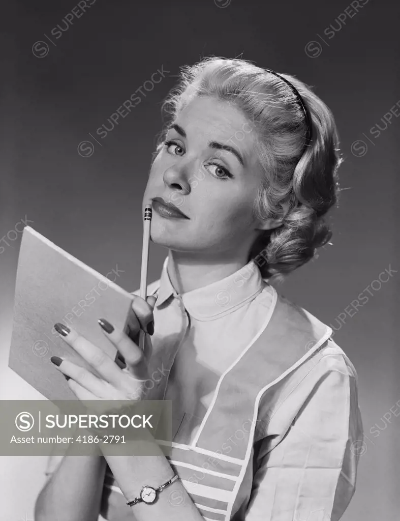 1950S Blond Woman Wearing Apron Writing Pad In Hand Pencil To Chin Thinking