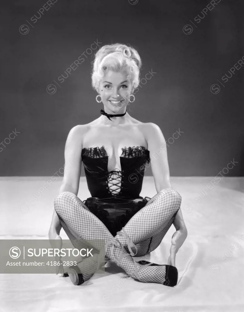 1960S Blonde Cheesecake Portrait Of Woman Wearing Black Camisole Corset And Fishnet Stockings