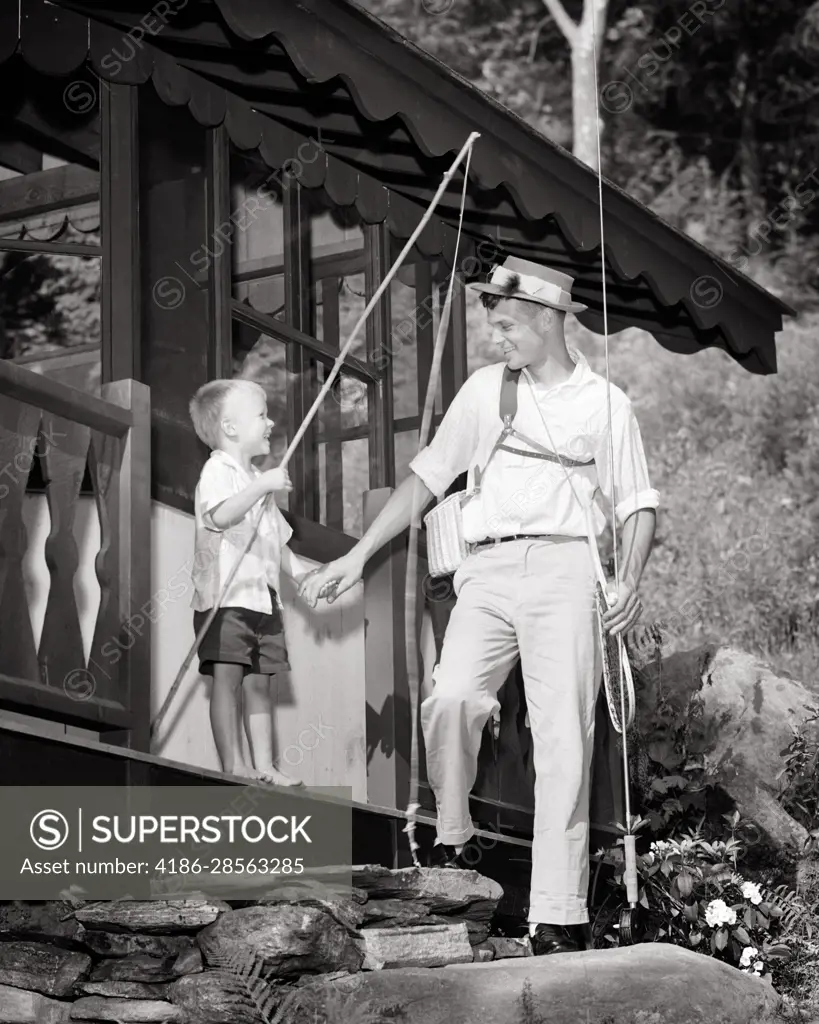1950s LITTLE BAREFOOT BOY WITH FISHING POLE HOLDING HANDS WITH DAD WITH  FISHING GEAR TO GO FLY FISHING IN FRONT OF CABIN - SuperStock