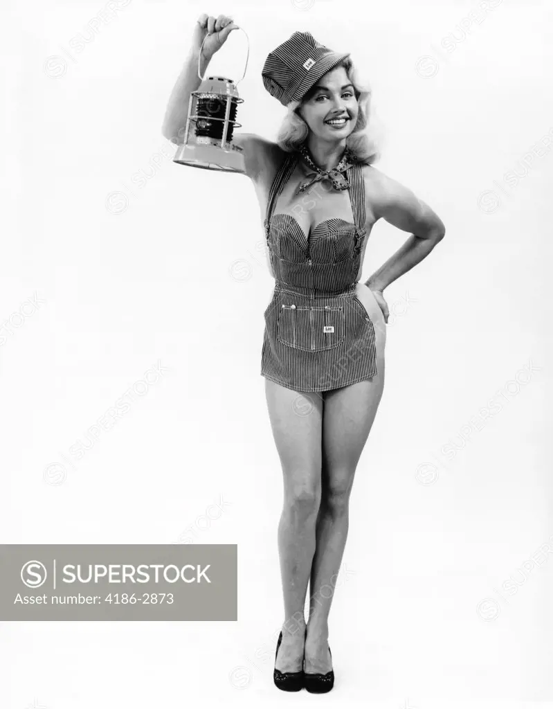 1950S Full Length Portrait Of Blond Woman Dressed In Railroad Apron & Cap Holding Signal Lamp Pinup