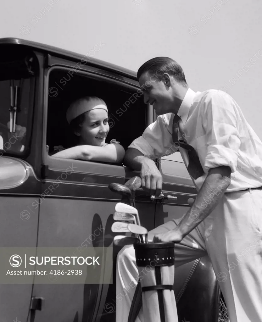 1930S Woman In Driver'S Seat Of Car Leaning Out Of Window Talking To Man Standing With Golf Bag
