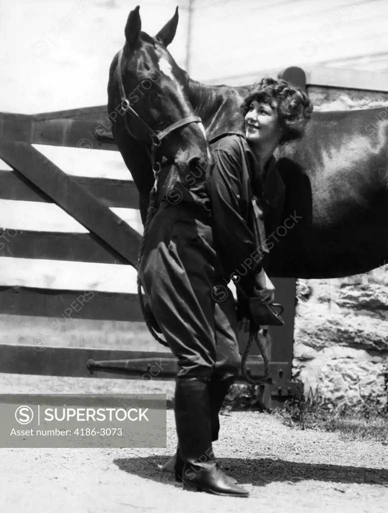 1900S 1910S Young Woman With Upswept Hair Lifting Front Leg Of Horse Checking Cleaning Hoof