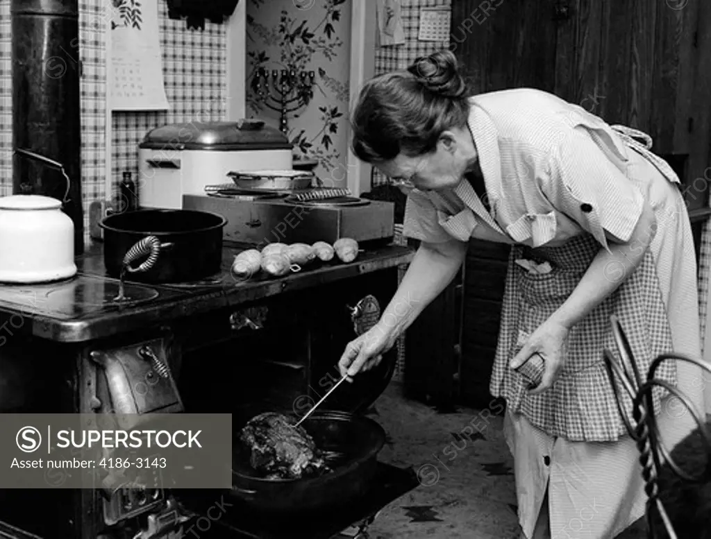 1950S Housewife Testing Roast Beef In Oven To See If It Is Done Cooking