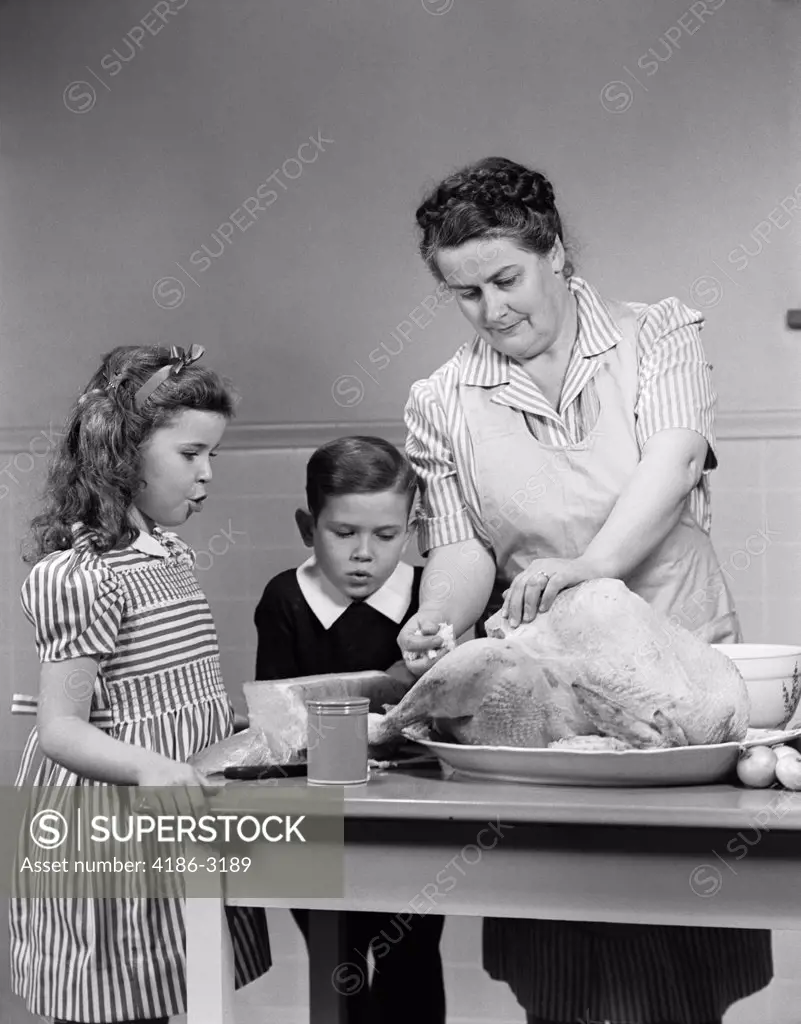 1940S Mother Son Daughter In Kitchen Stuffing Turkey For Thanksgiving Dinner
