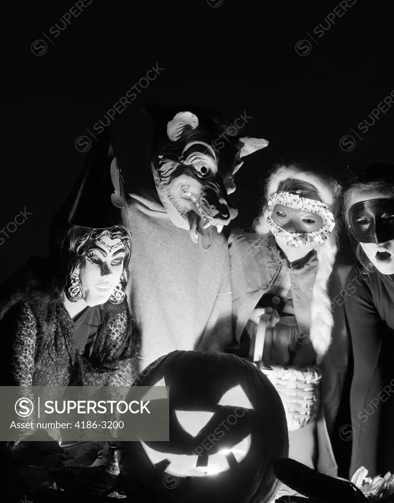 1960S Group Of Four Children In Halloween Costumes Gathered Around Jack-O'-Lantern Indoor