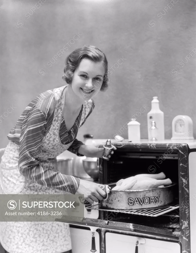 1930S Housewife In Apron Taking Turkey In Pan Reading Savory Out Of Oven