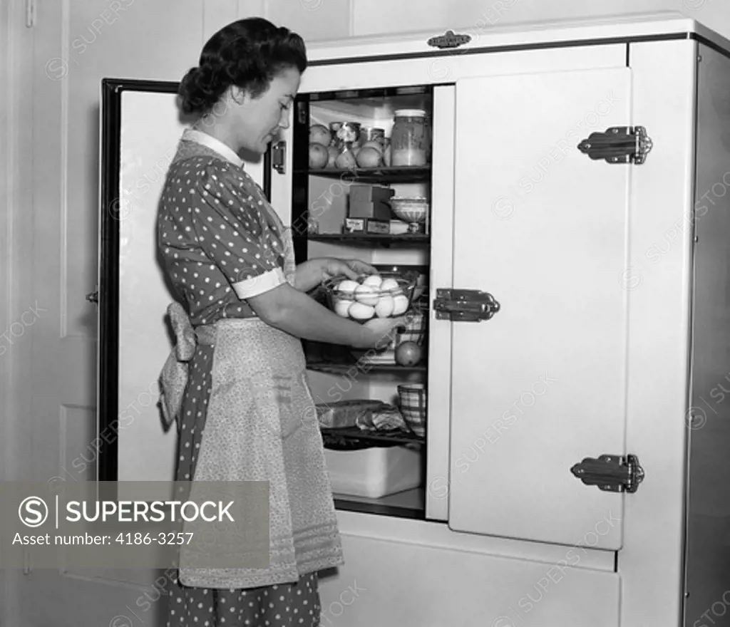1930S Housewife In Apron Taking Eggs Out Of Bowl From Icebox