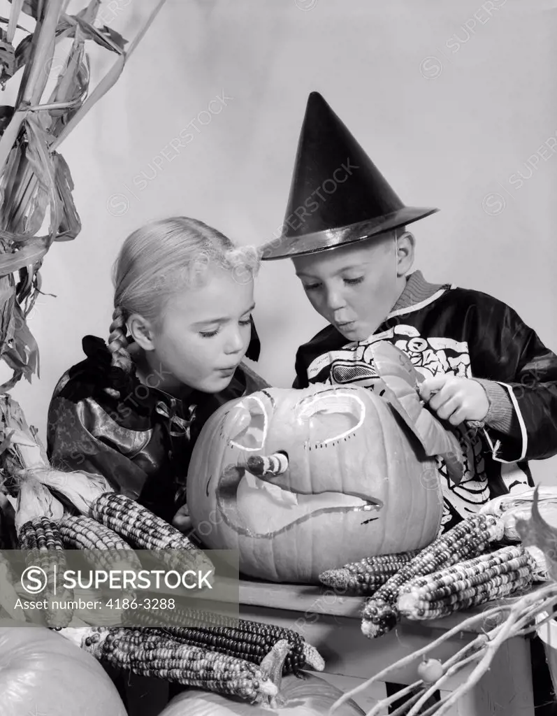 1960S Boy And Girl In Halloween Costumes Looking Into Pumpkin Indoor