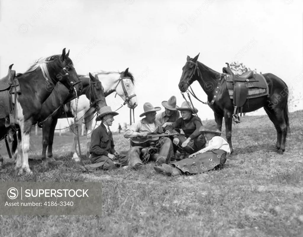 1920S 1930S Group Of Five Cowboys Sitting By Their Horses One Holds Guitar Singing