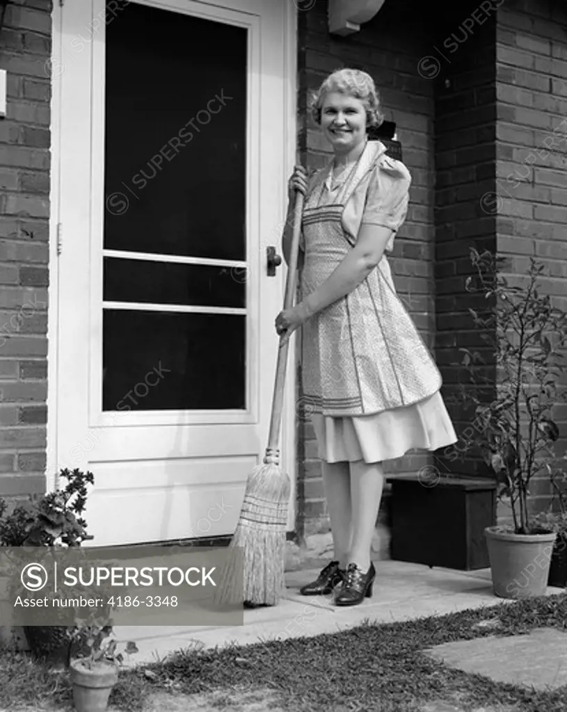 1940S Smiling Woman Sweeping Porch Front Door Step With A Broom