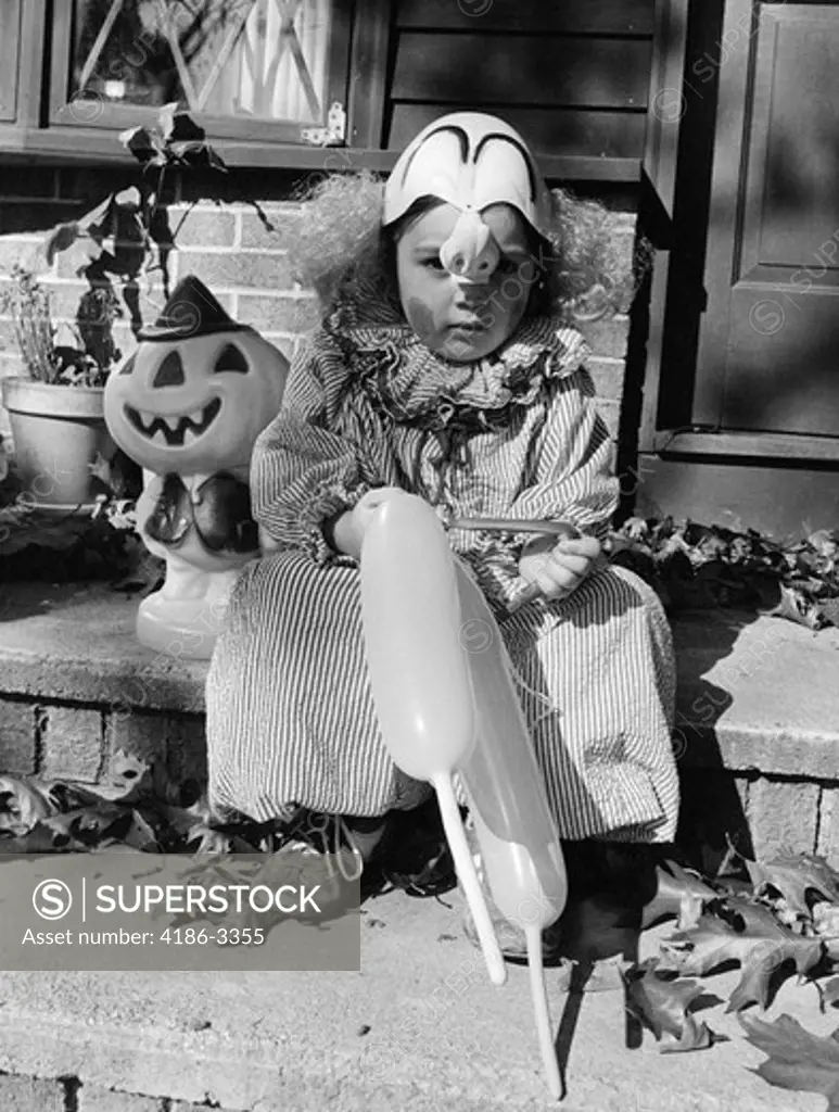 1970S Child In Trick Or Treat Clown Costume Sitting On Front Door Step Holding Balloons