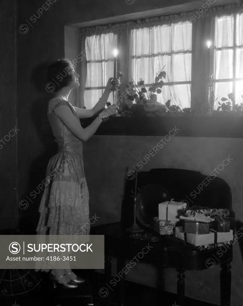 1920S Woman Party Dress Ruffles On Skirt Placing A Lighted Candle In Window Gifts Presents Wrapped On Side
