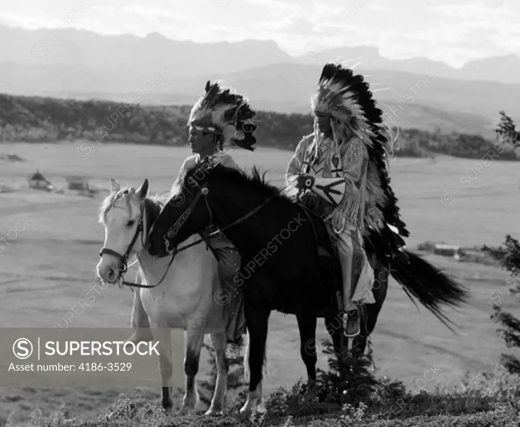 1930S Pair Of Sioux Indians Wearing Headdresses On Horseback