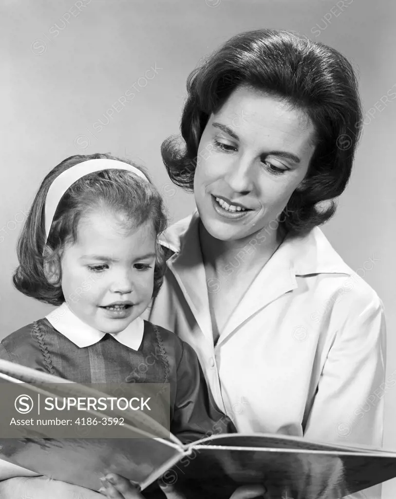 1960S Woman Reading Story Book To Girl Child