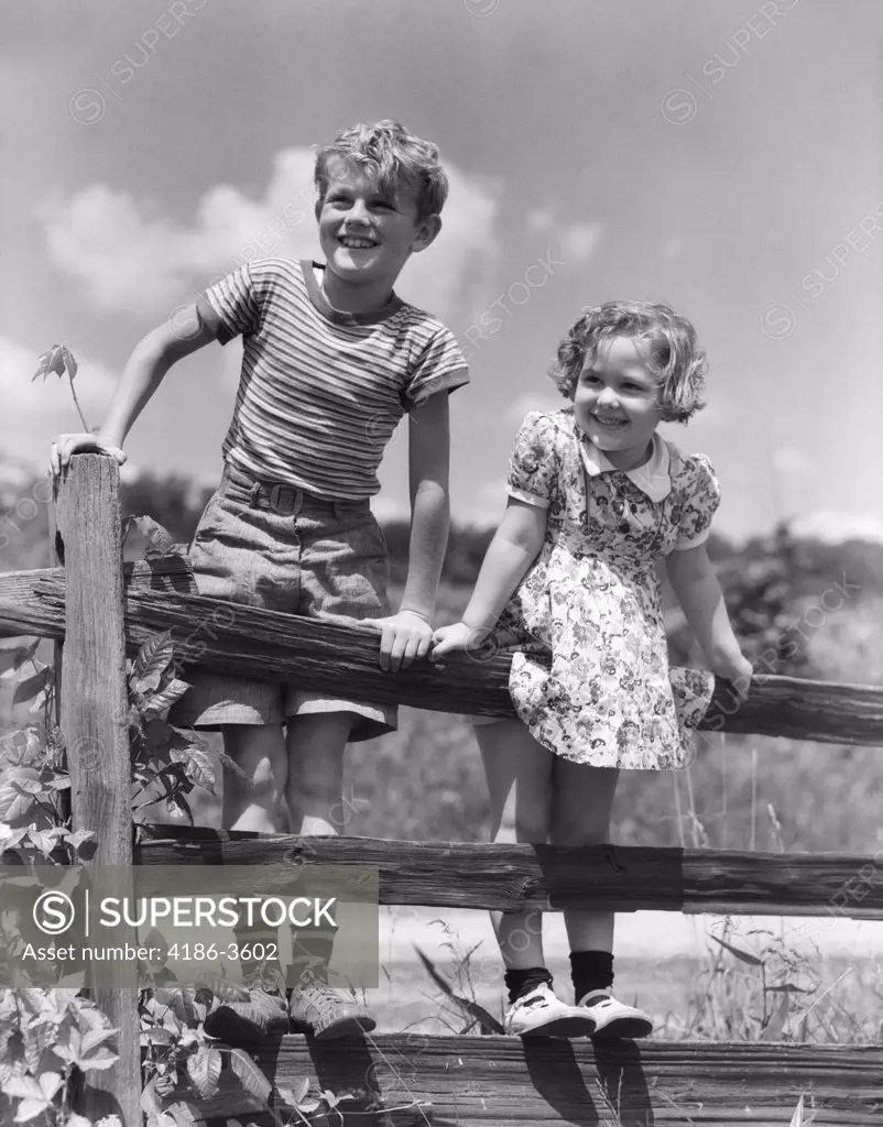 1930S Children Blond Boy And Girl Standing Together On Wooden Split Rail Fence Smiling