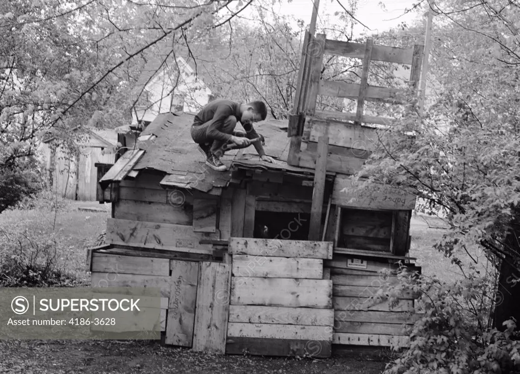 1960S Boy On Roof Of Shack House Fort Castle Nailing Down Shingle With Hammer
