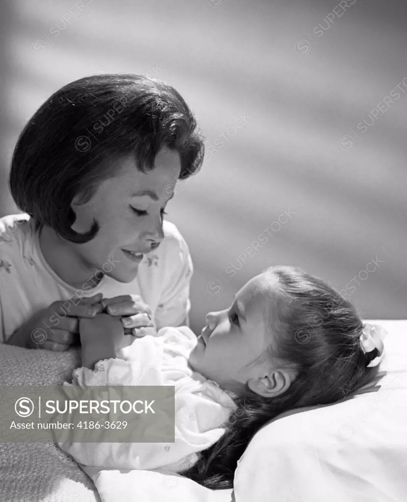 1960S Daughter With Mother Tucking Into Bed