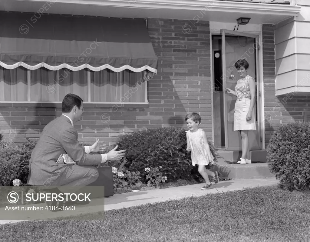 1960S 1970S Little Girl Running To Greet Father On Sidewalk Mother At Front Door