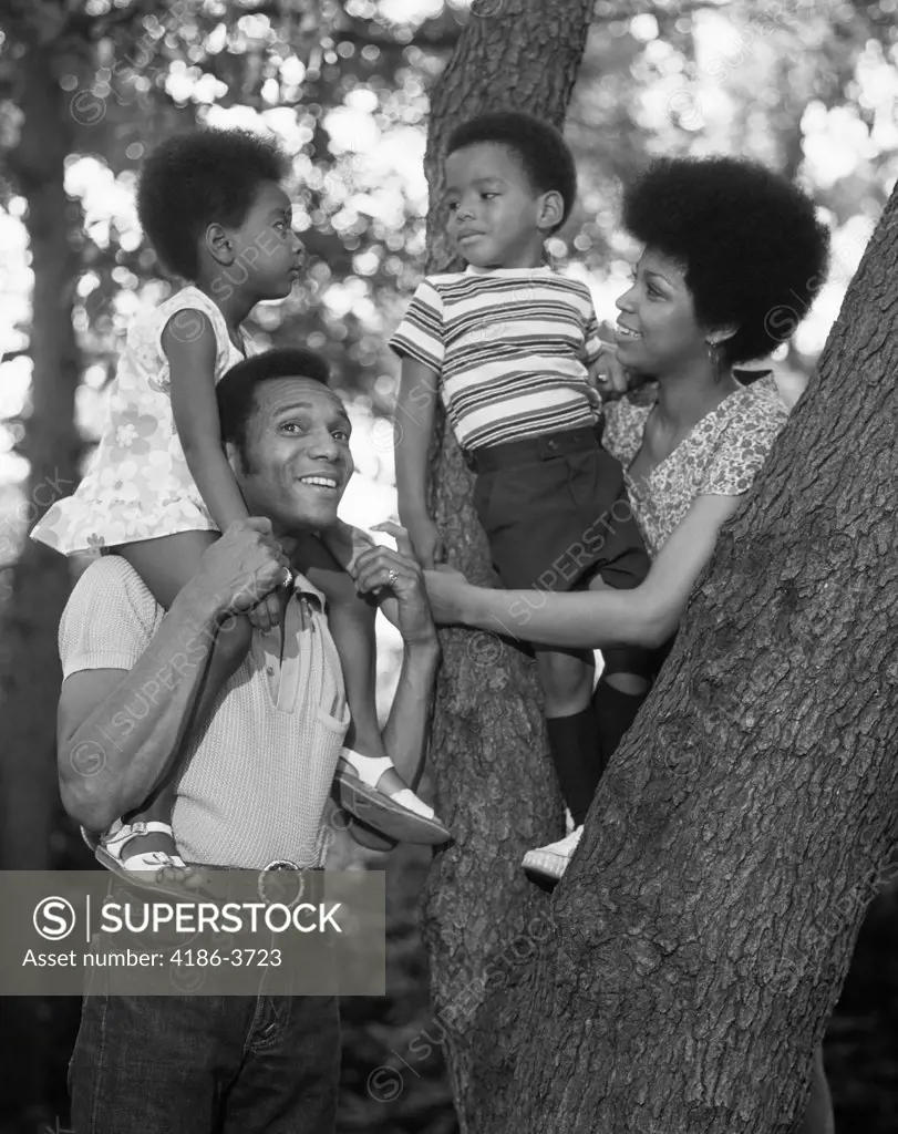 1970S African American Family Outdoors By Trunk Of Tree Mother Father Boy Girl