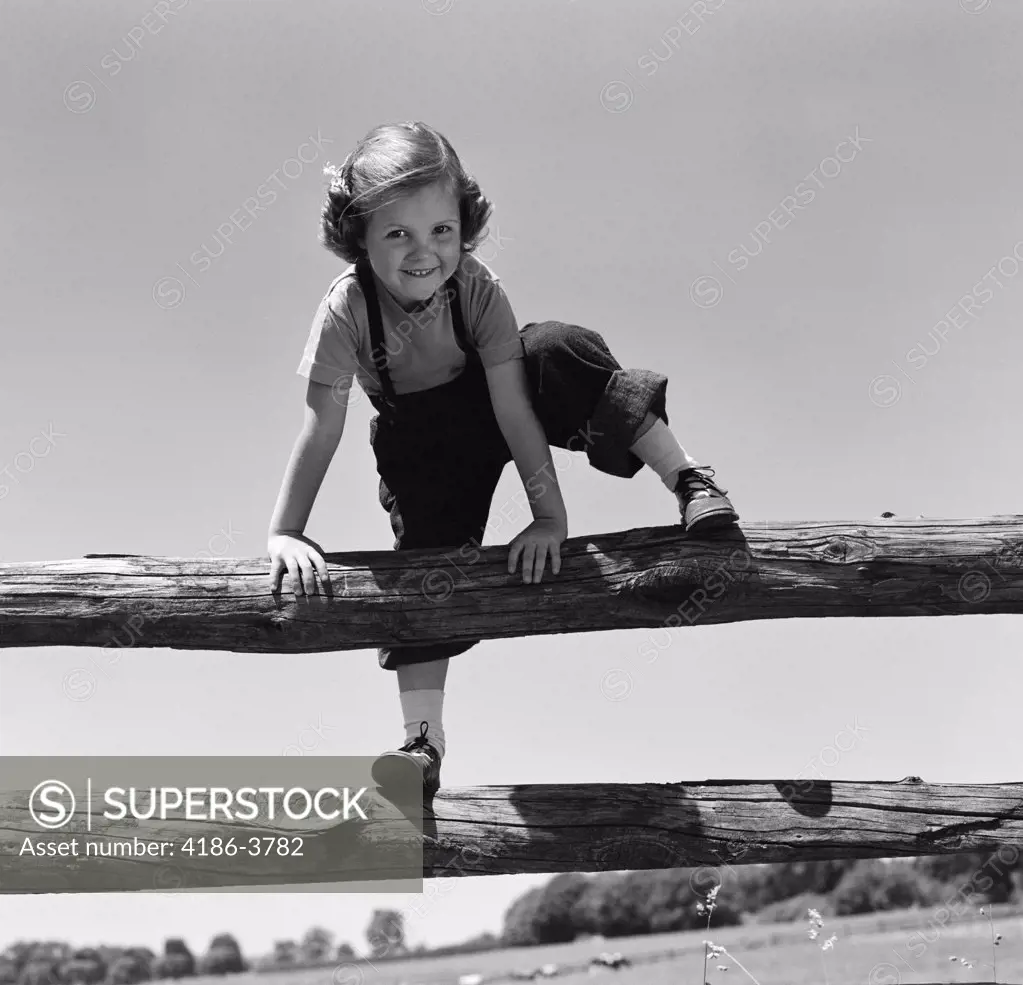 1940S 1950S Smiling Girl Climbing Over Wooden Fence