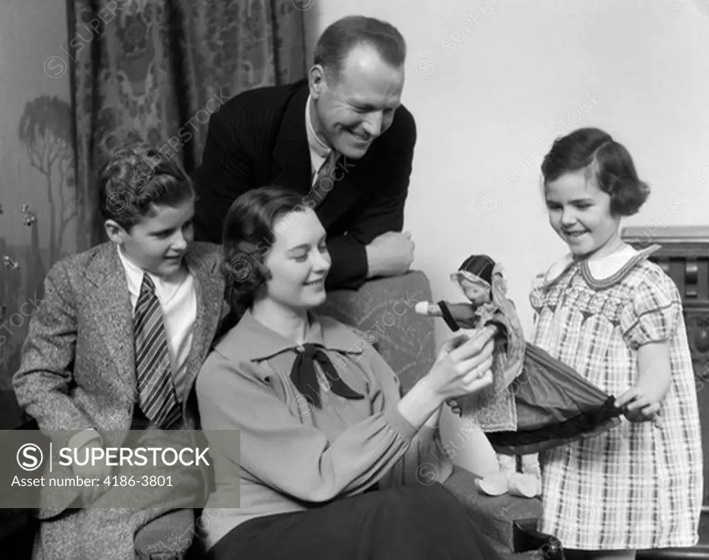 1930S Family Of Four Gathered Around Looking At Daughter'S Dutch Girl Doll