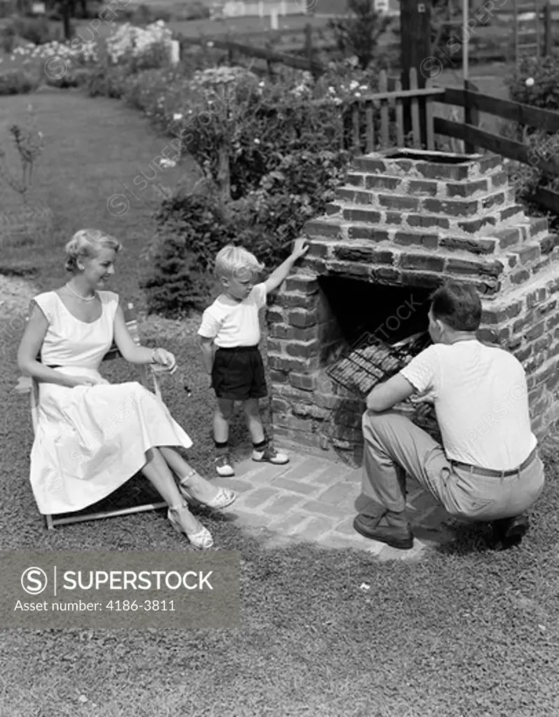 1940S 1950S Family In Backyard Cooking Hamburgers On Brick Barbeque