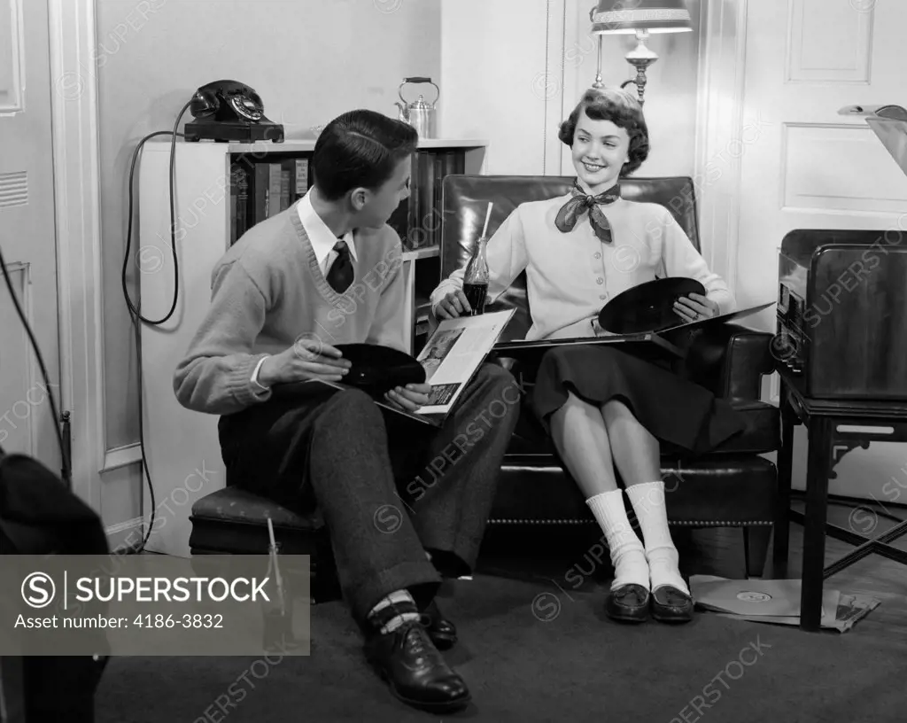 1950S Teen Boy & Girl Sitting In Living Room Drinking Soda & Listening To Records