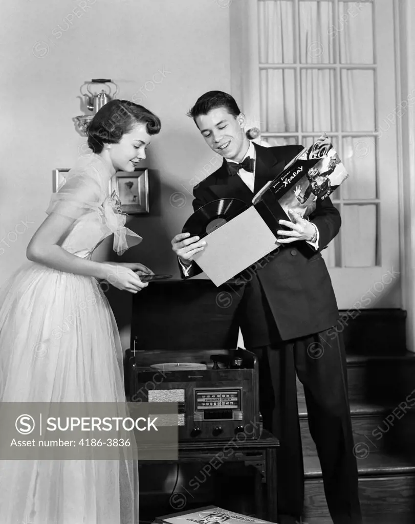 1950S Teen Couple Boy And Girl In Prom Formal Wear Playing Phonograph Records In Home Living Room