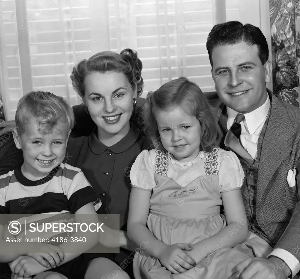 1950S Portrait Of Smiling Family Man Father Woman Mother Boy Son Girl Daughter Sitting On Living Room Sofa