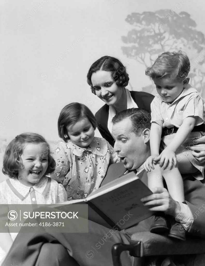 1930S Family Of Five Grouped Around Father Reading Children'S Punch Book