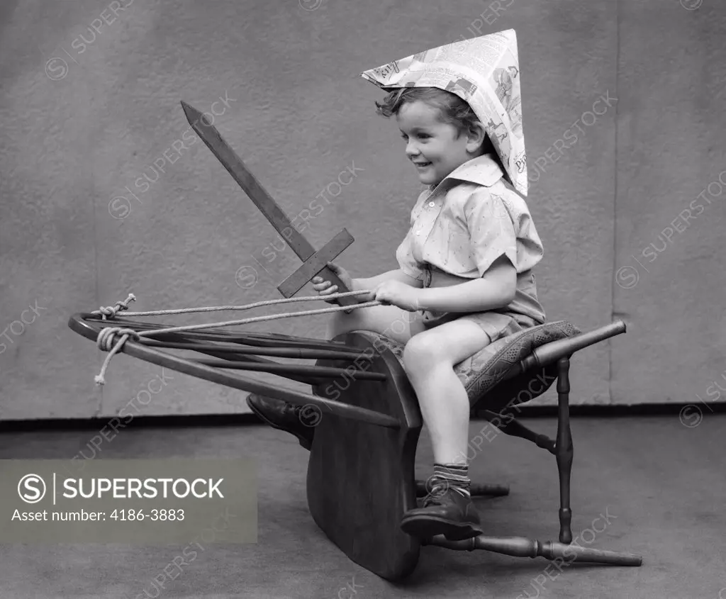 1930S Boy Playing Wooden Sword Paper Hat Riding Chair Like A Horse