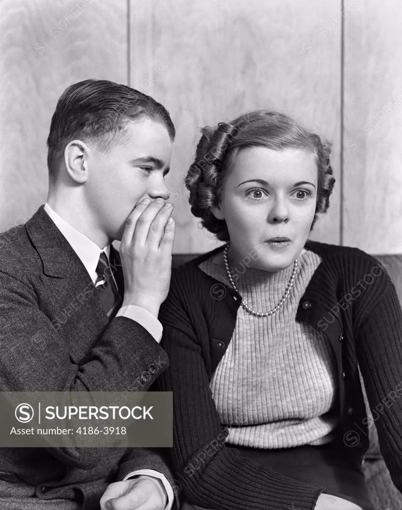 1940S 1930S Young Teenage Couple Boy Whispering Into Girl'S Ear Girl With Amazed Surprised Expression