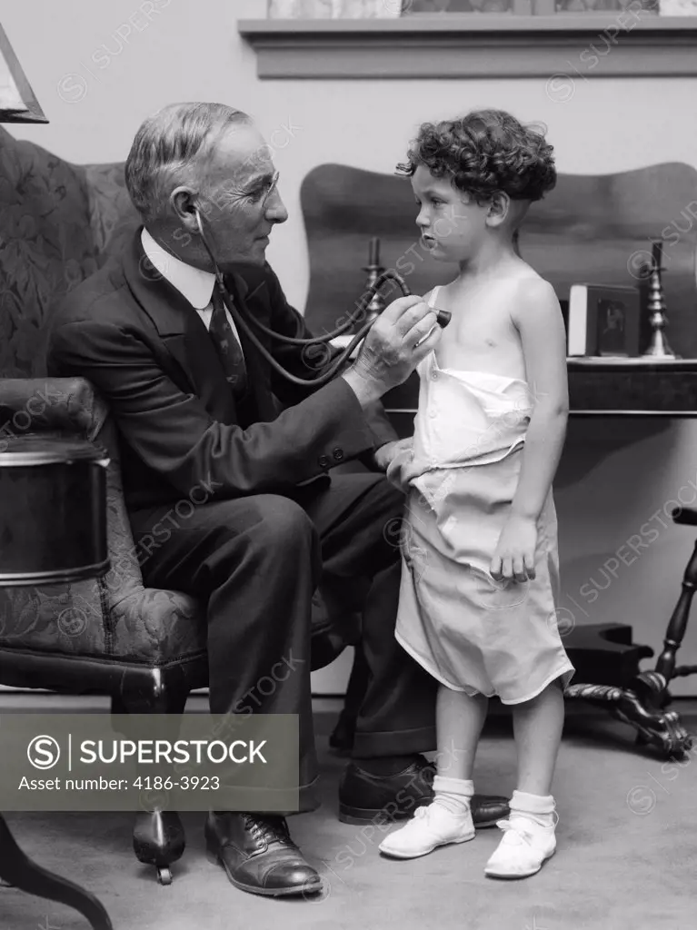 1930S Man Doctor Making House Call Holding Stethoscope To Chest Of Little Boy Patient