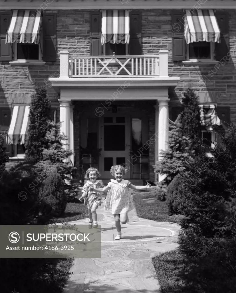 1930S 2 Girls In Summer Dresses Running To Camera On Flagstone Sidewalk In Front Of House