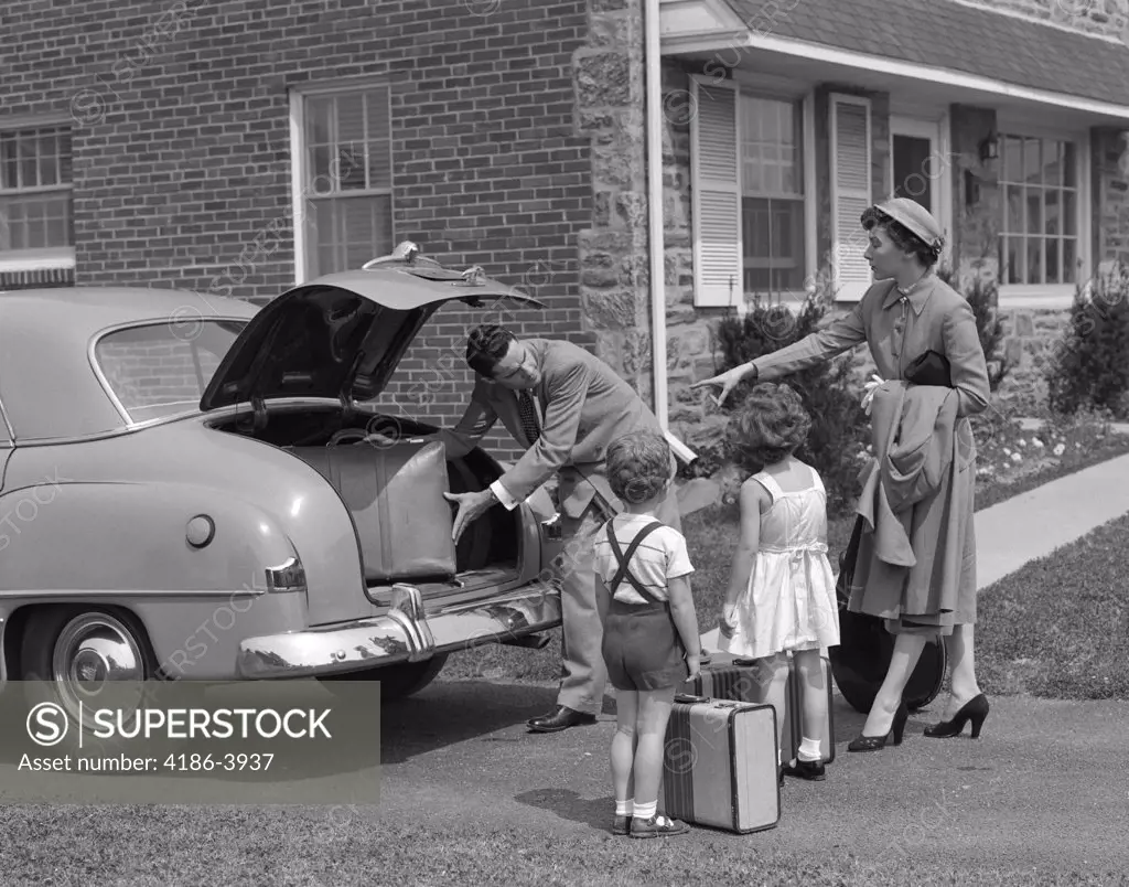 1950S Family Putting Luggage Suitcases Into Trunk Of Car