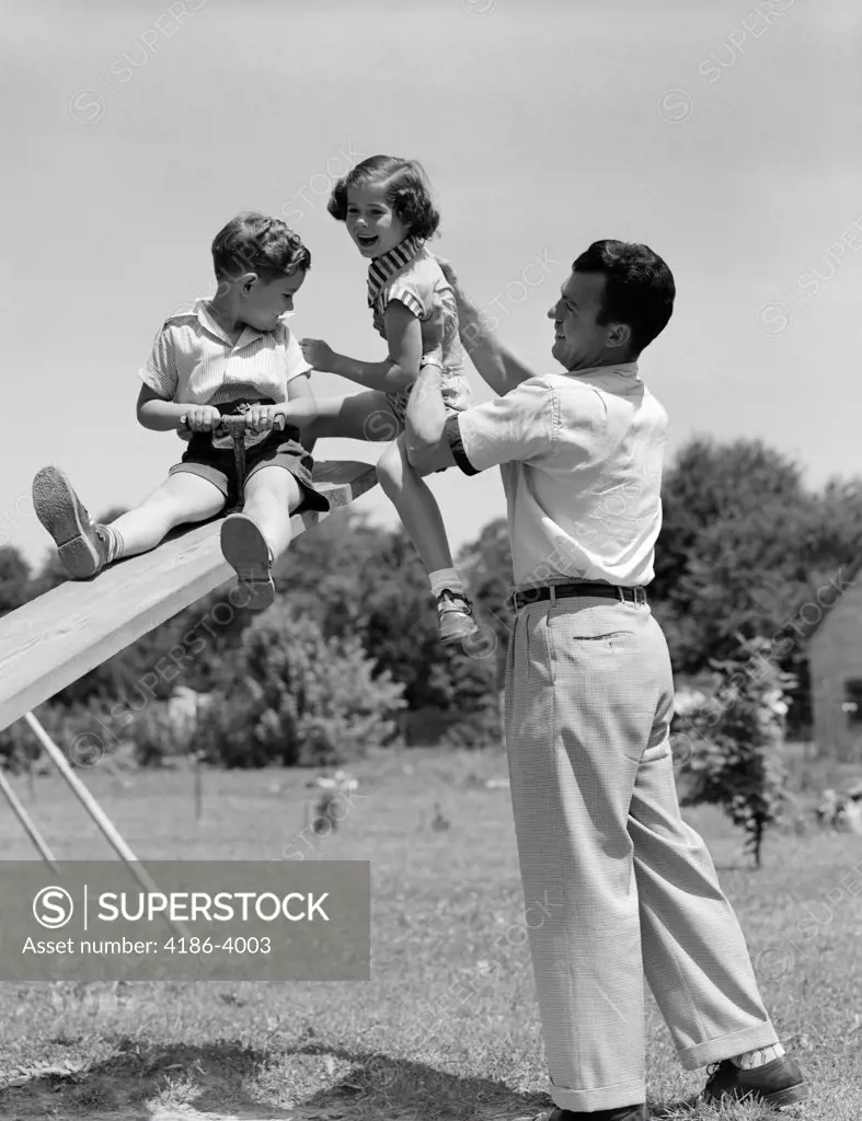 1950S Father Lifting Son And Daughter Onto A Playground Seesaw Outdoor