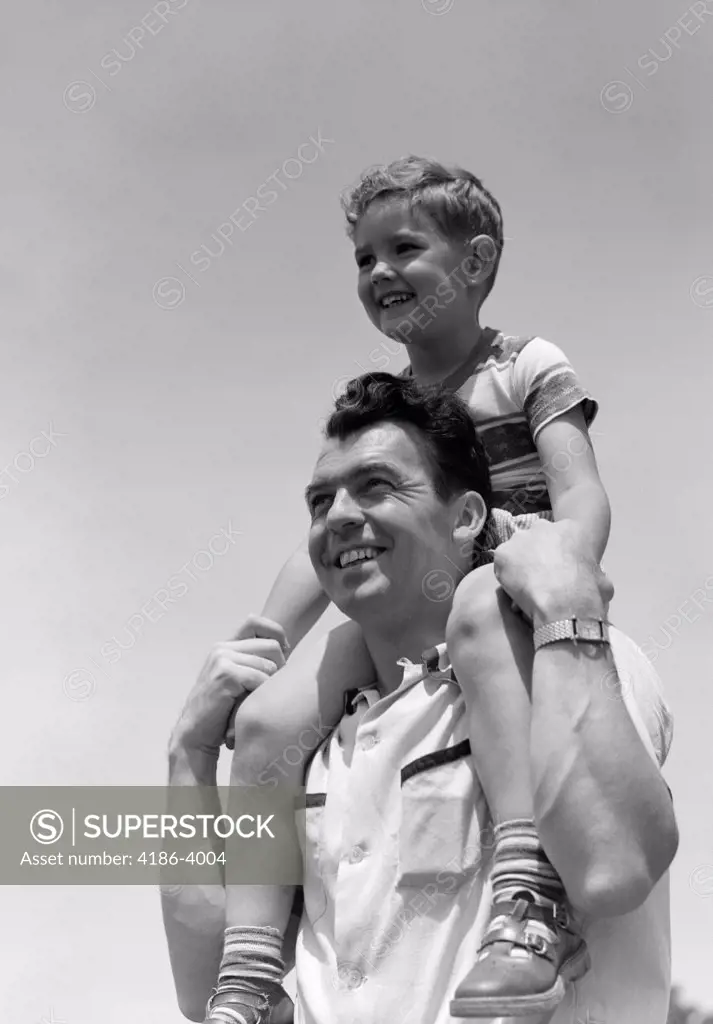1950S Smiling Father Carrying Son On Shoulders Outdoor