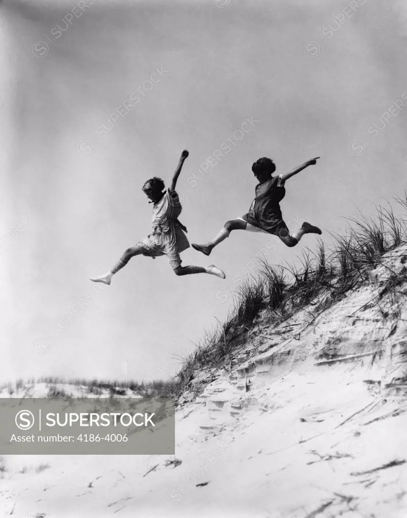 1920S 1930S Two Girls Midair Jumping Off Of Beach Sand Dune