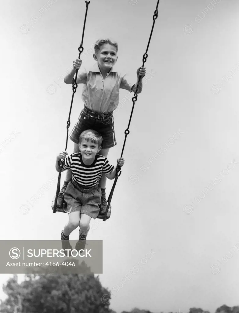 1930S Two Smiling Boys Sitting Standing On Playground Swing
