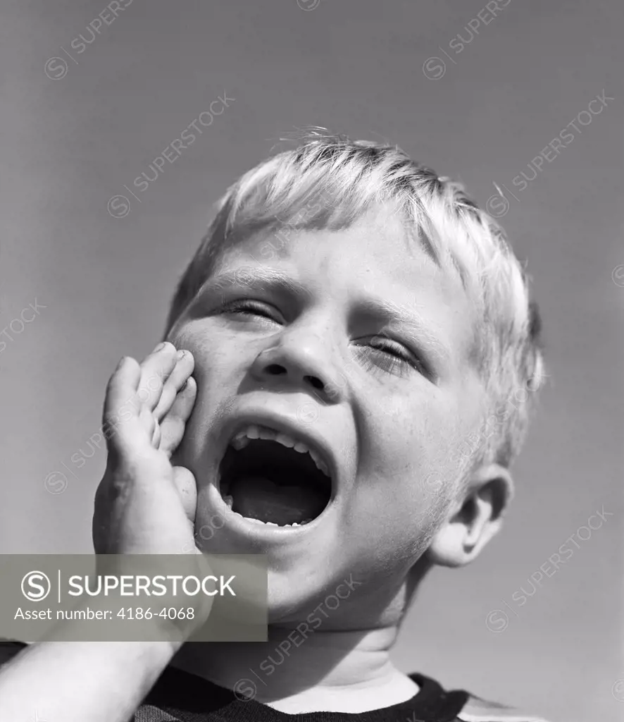 1950S Blond Boy With Eyes Closed And Hand Cupping A Wide Open Mouth Shouting
