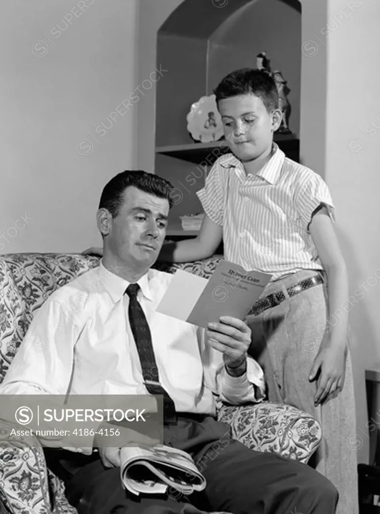 1950S Boy Standing Looking Down At Father Reviewing His Report Card