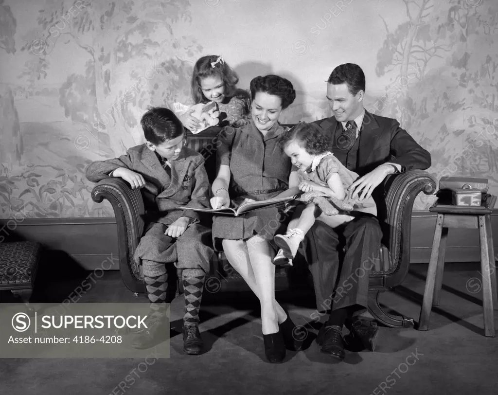 1940S Family Sitting On Couch Looking Reading Book