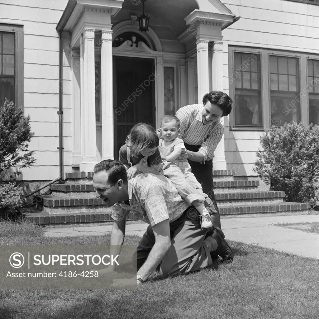 1950S Family Front Lawn House Two Kids Riding Father Piggyback Mother Helping Toddler Baby
